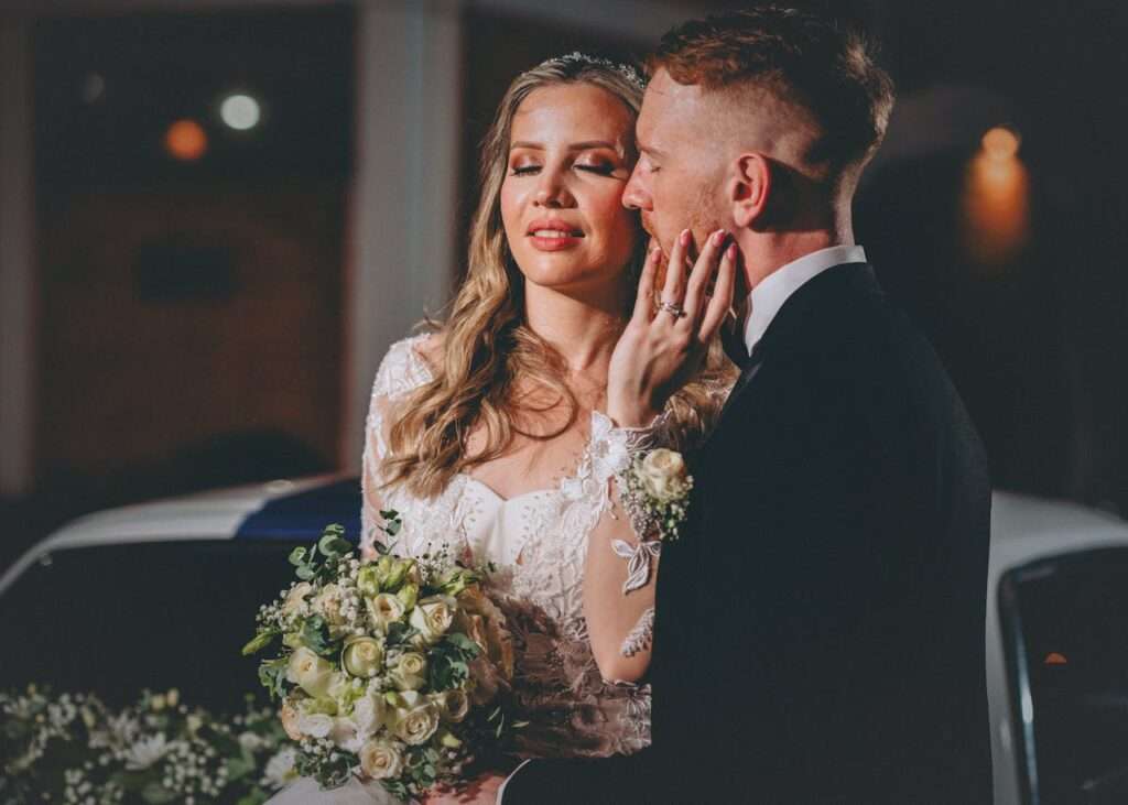 Cuplu de miri surprins într-un moment romantic, seara, în aer liber.